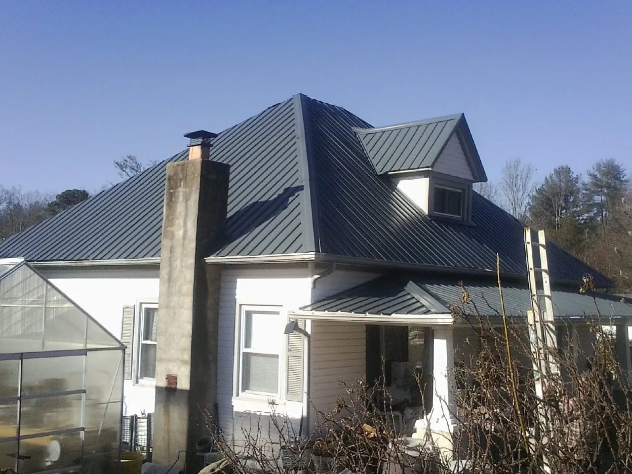 Dark blue standing seam metal roof on a white farmhouse with dormer — Slate & Tile Roof Repair by Roofing Brothers in Entriken