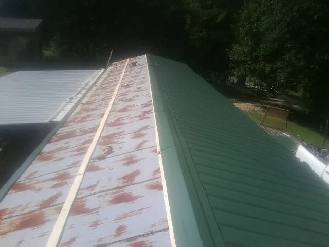 Old rusted panels beside newly installed green metal roofing — Wind Damage Roof Repair by Roofing Brothers in Entriken