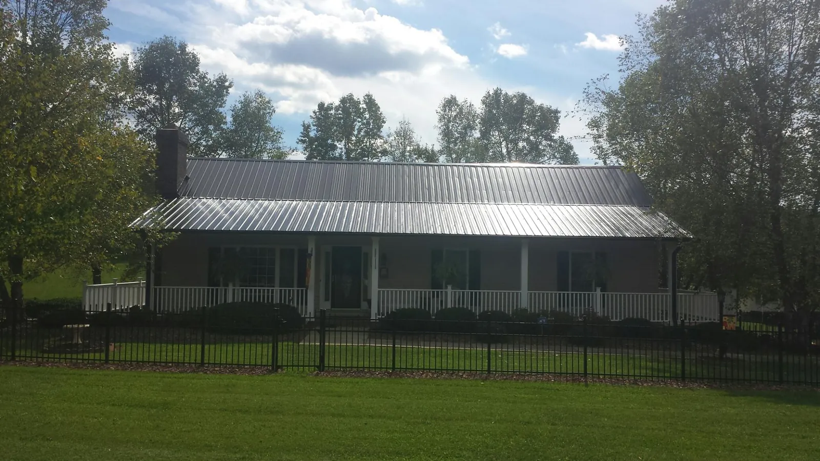 Gray metal roof on a brick ranch with a full width front porch — Gutter Guard Installation work by our crew in Entriken