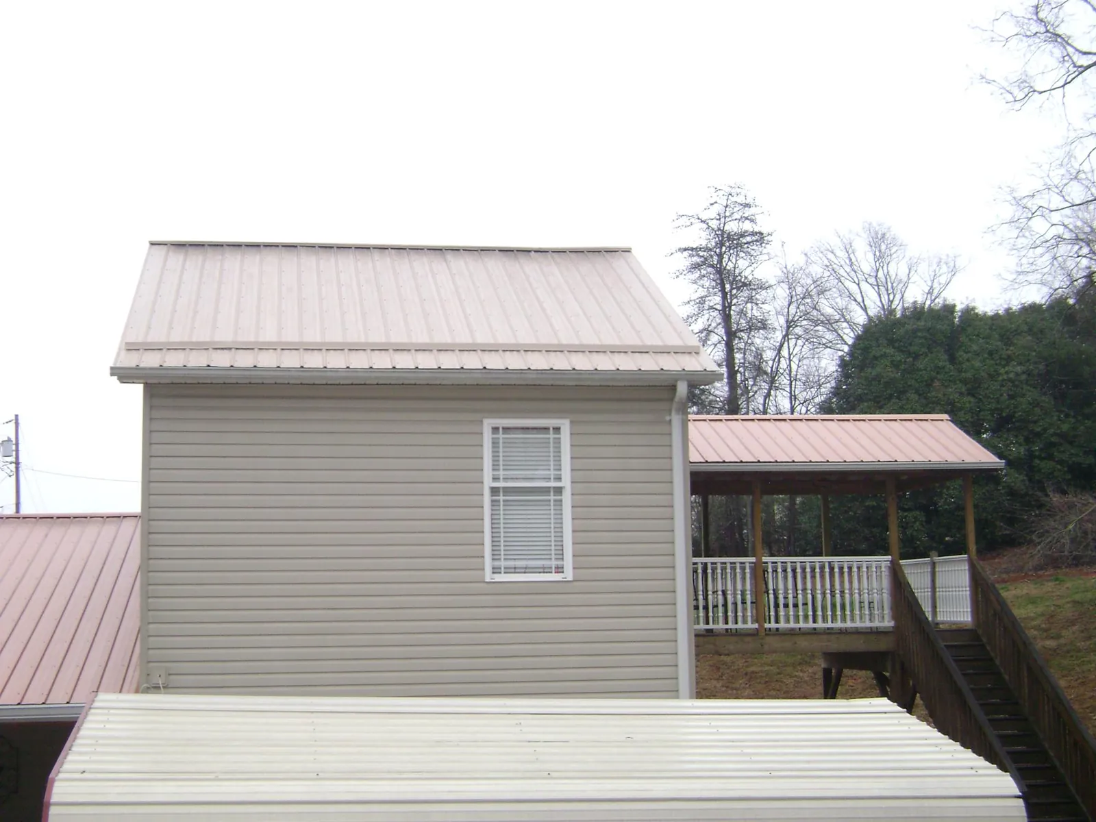 Tan metal roofs on a two story addition and attached porch, from a Roof Replacement job in Entriken