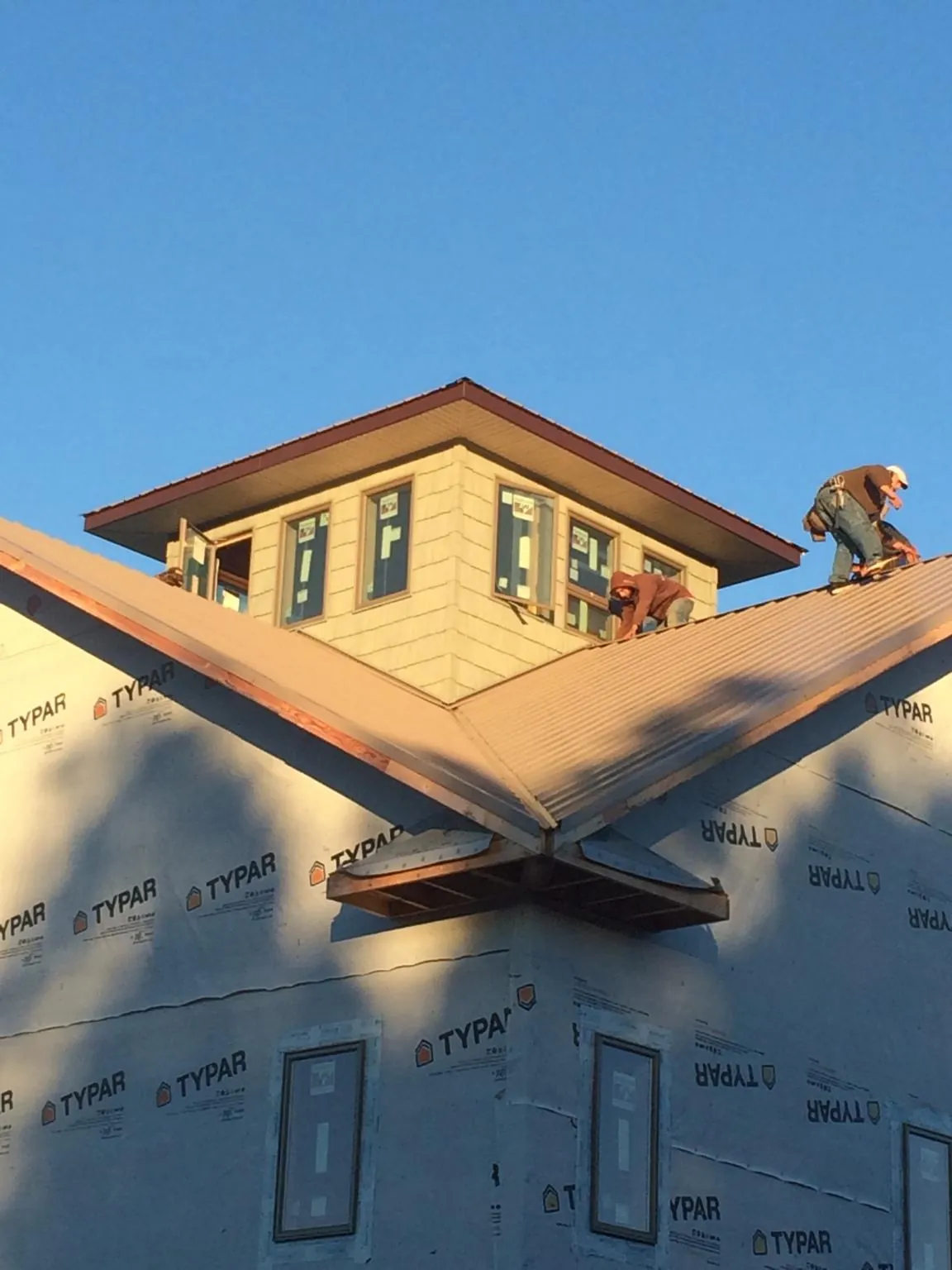 Roofers working around a rooftop cupola on a new metal roof at sunset — Roof Waterproofing in Entriken by Roofing Brothers